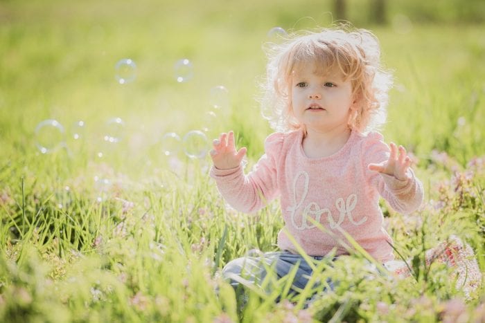 toddler playing with bubbles in nature